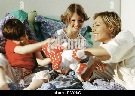 Familie spielt mit Kuscheltier im Bett, Lächeln Stockfoto