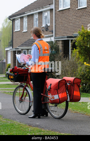 Royal Mail Briefträgerin sortieren Briefe auf ihrer Runde Stockfoto