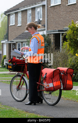 Royal Mail Briefträgerin sortieren Briefe auf ihrer Runde Stockfoto