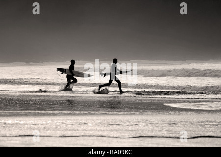 Zwei Surfer laufen in die Wellen Chesterman Beach in der Nähe von Tofino, auf Vancouver Island, British Columbia, Kanada. Stockfoto