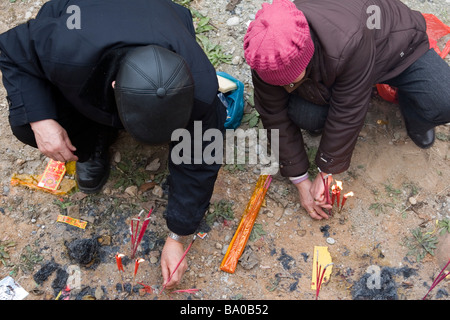 Menschen, Opfergaben an Kerzen, Räucherstäbchen und brennenden Papiergeld die Geister der Vorfahren in China zu besänftigen. Stockfoto