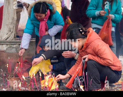 Menschen, Opfergaben an Kerzen, Räucherstäbchen und brennenden Papiergeld die Geister der Vorfahren in China zu besänftigen. Stockfoto