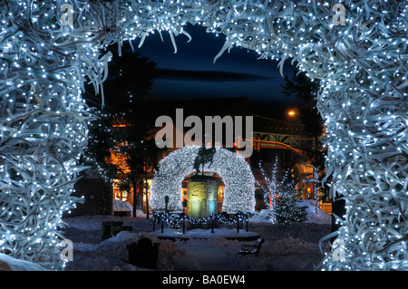 Helle Weihnachtsbeleuchtung auf Elch Geweih Bögen in Jackson Wyoming USA Altstädter Ring im Winter in der Dämmerung mit Cowboy auf bucking Broncho-statue Stockfoto