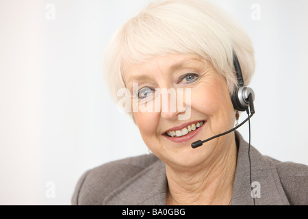 Professionelle senior Geschäftsfrau trägt Kopfhörer Stockfoto