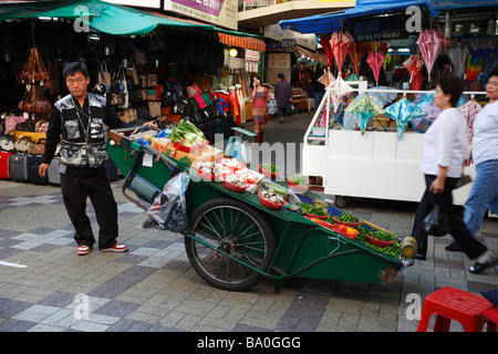 Ein Kaufmann seine frische Produkte für den Verkauf auf einen großen Wagen in der Mitte der Straße Marktplatz in der Stadt Busan anzeigen Stockfoto