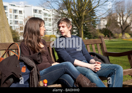 Junges Paar sprechen und entspannen Sie sich in einem öffentlichen Park in England, UK Stockfoto