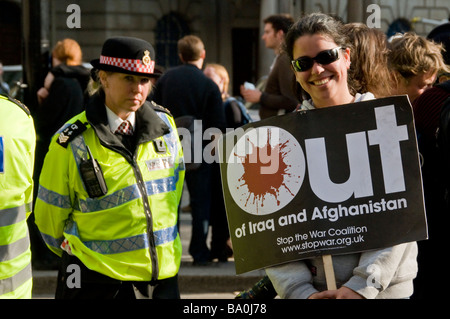 Ein junges Mädchen Demonstrant posiert mit einer Anti-Kriegs-Banner und eine Polizistin im Hintergrund, G20-Gipfel protestiert, London, England Stockfoto