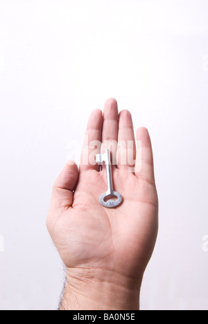 Hand, die einen Hausschlüssel vor einem weißen Hintergrund Stockfoto