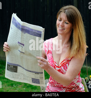 Frau Kleinanzeigen in der Zeitung lesen Stockfoto