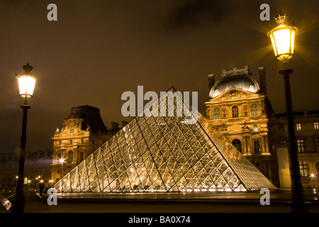 Der Louvre-Pyramide-Paris-Frankreich beleuchtet in der Nacht mit Spiegelbild im Wasser Stockfoto