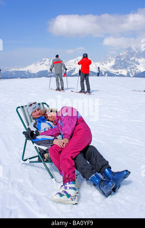 junges Paar ruht auf einer Leinwand-Stuhl auf der Reiteralm in der Steiermark, im Hintergrund Dachstein-Gebirge, Österreich Stockfoto