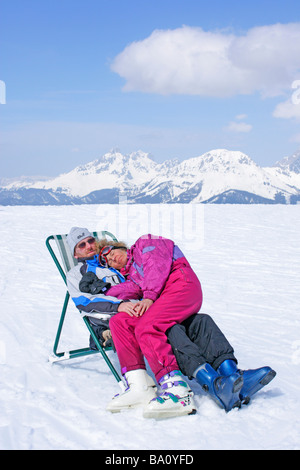 junges Paar ruht auf einer Leinwand-Stuhl auf der Reiteralm in der Steiermark, im Hintergrund Dachstein-Gebirge, Österreich Stockfoto
