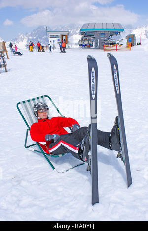 ein Teenager ruht in einem Leinwand Stuhl auf der Reiteralm in der Steiermark, im Hintergrund Dachstein Gebirge, Österreich Stockfoto