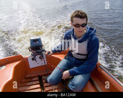 Junger kaukasischer Rüde, der eine Kill Cord trägt, während er ein Motorboot auf dem Fluss Ouse in York steuert. VEREINIGTES KÖNIGREICH Stockfoto