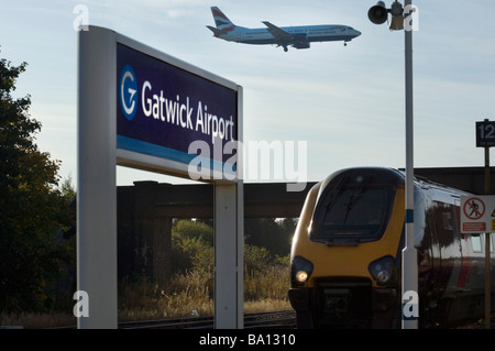 Eine British Airways Flugzeug landet über dem Bahnhof am Flughafen Gatwick, wie ein Zug darunter kommt. Stockfoto