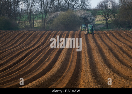 Traktoren arbeiten in einen Acker in der Landschaft von Suffolk, England. Stockfoto
