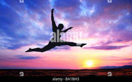 Eine Silhouette eines springenden Menschen auf einem farbenfrohen Sonnenuntergang Hintergrund Stockfoto