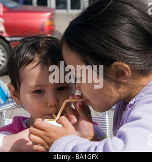 Zwei junge halb-Thai-Schwestern auf ihre Sommerferien trinken aus der gleichen Milchshake-Flasche durch Strohhalme Stockfoto