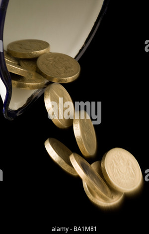 Ein Pfund und zwei Pfund-Münzen eine Emaille-Kanne ausgießen Stockfoto