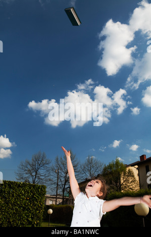 Kind feiert Ende Schuljahr ein Buch in die Luft werfen Stockfoto