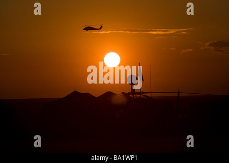 Camp-Speicher, Irak - UH-60 Blackhawk fliegt über Camp Speicher Flugplatz bei Sonnenuntergang. Stockfoto