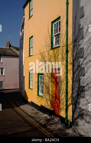 Ein Ferienhaus in Lyme Regis gemalt frisch helles Gelb mit grünen Dachrinnen und Fenster umgibt und eine orange Tür Stockfoto