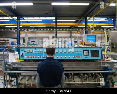 Mann am Bedienfeld des industriellen Maschinen, die für die Herstellung von schöner Kanten auf Glasplatten verwendet wird Stockfoto
