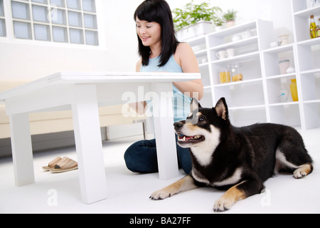 Junge Frau sitzt am Boden durch Tabelle mit Akita Hund niedrigen Winkel Ansicht Stockfoto