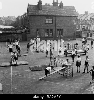 1950s, historische, junge Kinder mit einer traditionellen körperlichen Bildung (PE) Klasse auf einem innerstädtischen Grundschule Spielplatz, London, England, Großbritannien. Stockfoto