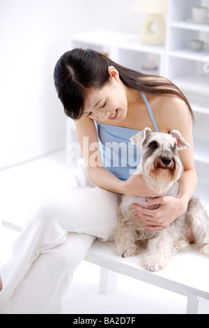 Junge Frau umarmt Wire Fox Terrier sitzen auf Bank erhöht, Ansicht Stockfoto