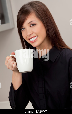 Eine schöne junge orientalische Frau mit einem wunderbaren toothy Lächeln aus einem weißen Becher trinken Stockfoto