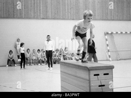 70er Jahre, schwarz / weiß Foto, Erbauung, Schule, Sport, Sportunterricht, Sportunterricht, Gymnastik, Sporthalle, kleiner Junge auf einem gymnastischen Apparat, im Alter von 5 bis 8 Jahre Stockfoto