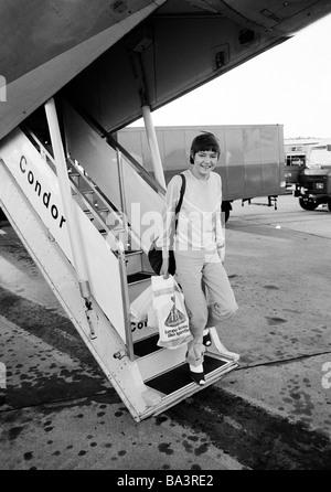 Achtziger Jahre, schwarz / weiß Foto, Menschen, junge Frau Blätter eine Schallmauer mit der Gangway, Pulli, Hose, Handtasche, Plastiktüten mit waren aus dem Duty free Shop, Condor, Handgepäck, im Alter von 25 bis 35 Jahre, D-Düsseldorf, Rhein, Nordrhein-Westfalen Stockfoto