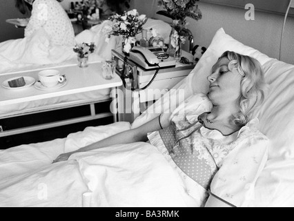 Achtziger Jahre, schwarz / weiß Foto, Menschen, Gesundheit, junge Frau liegt in einem Krankenbett eines Krankenhauses, im Alter von 30 bis 40 Jahre, Elisabeth Stockfoto