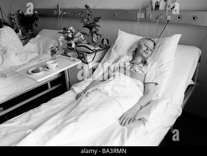 Achtziger Jahre, schwarz / weiß Foto, Menschen, Gesundheit, junge Frau liegt in einem Krankenbett eines Krankenhauses, im Alter von 30 bis 40 Jahre, Elisabeth Stockfoto