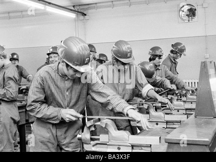 70er Jahre, schwarz / weiß Foto, Bildung, job Ausbildung, Ausbildung, Handwerk, Shop, Werkstatt, Lehrwerkstätte, junge tragen Schutzhelme arbeiten bei einer Maschinendrehbank, Jugendliche im Alter von 14 bis 17 Jahre Stockfoto