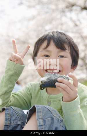 Japanische junge Verzehr von Sushi und zeigt V Zeichen Stockfoto