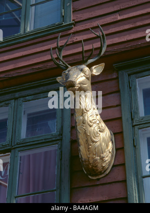 Golden geschnitzter Kopf eines Hirsches auf einem alten Holzlager am Wasser, Bryggen, Bergen, Hordaland, Norwegen. Stockfoto