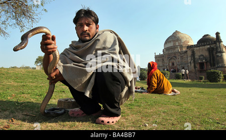 Ein Schlangenbeschwörer in Neu-Delhi ruhigen Lodhi Gärten hockt vor dem Sheesh Gumbad Grab seine Ware anzeigen Stockfoto