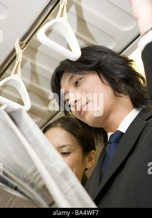 Unternehmer Zeitung im Zug stehen neben einer Frau niedrigen Winkel Leseansicht Stockfoto