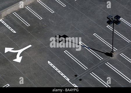 Schwarz / weiß Bild der Overhead, grafische Schuss von einem frisch gestrichenen Parkplatz mit Lichtmast, Pfeile und dramatischen Schatten. Stockfoto