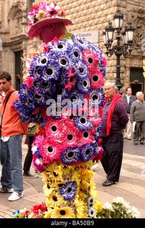 Ein Gesicht gemalt, führt Streetart-Künstler in bunten Blumen gekleidet auf Los Rambla in Barcelona, Spanien mit Leute zu beobachten. Stockfoto