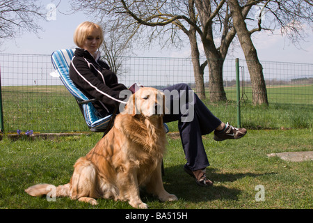 Frau und golden Retriever entspannend im Garten an einem warmen Frühlingstag. Stockfoto