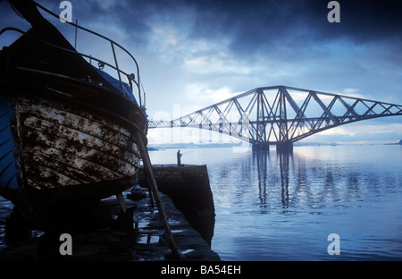 Her-Eisenbahnbrücke mit alten Holz-Boot im Vordergrund schoss aus South Queensferry Hafen. Stockfoto