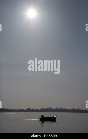 kleine einzelne einsamen Fischer ausgehen in einem kleinen motorisierten Angelboot/Fischerboot in der Sonne am Lough Neagh Grafschaft Armagh Irland Stockfoto