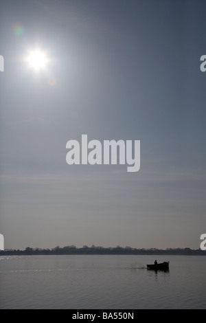 kleine einzelne einsamen Fischer ausgehen in einem kleinen motorisierten Angelboot/Fischerboot in der Sonne am Lough Neagh Grafschaft Armagh Irland Stockfoto