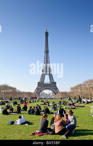 PARIS, Frankreich – die Menschen entspannen sich und genießen den Sonnenschein an einem Frühlingsmorgen im Parc du Champ de Mars, mit dem berühmten Eiffelturm, der sich im Hintergrund erhebt. Besucher und Einheimische profitieren gleichermaßen von dem angenehmen Wetter in diesem beliebten öffentlichen Grüngelände. Stockfoto