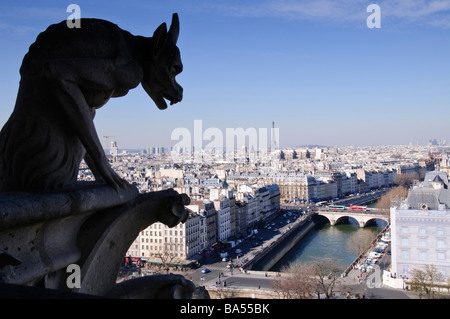 Kathedrale Notre Dame Gargoyle Paris Skyline Eiffelturm seine Paris Frankreich | PARIS, Frankreich — Ein Steinchimera auf der Notre-Dame de Paris blickt über die Dächer der Île de la Cité, in der Ferne erhebt sich der Eiffelturm. Diese skulpturalen Grotesken, die während der Restaurierung Viollet-le-Duc im 19. Jahrhundert hinzugefügt wurden, sind so erkennbar geworden wie die gotischen Türme der Kathedrale selbst. Die seine kurvt unten, durchquert von der Pont au Double und anderen historischen Brücken. Stockfoto