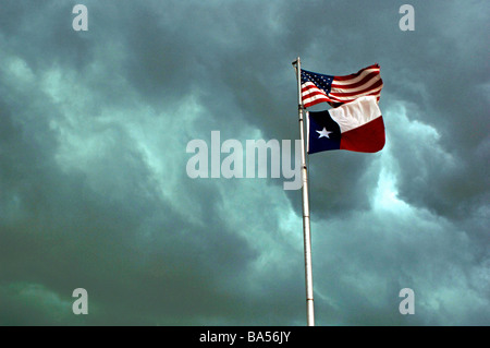 Dramatische dunkle Gewitterwolken sammeln über eine Fahnenstange mit den USA und Texas Flaggen Stockfoto