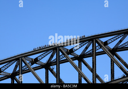 Klettern an der Sydney Harbour Bridge, NSW, Australien. Eine Gruppe von Kletterern in Silhouette gegen blauen Himmel Stockfoto